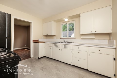 A kitchen with white cabinets and a black refrigerator.