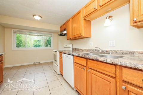 A kitchen with wooden cabinets and a marble countertop.