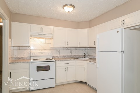A kitchen with white appliances and cabinets.