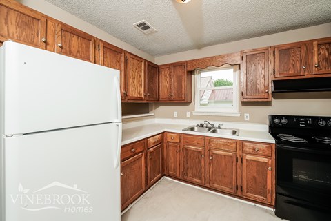 A kitchen with wooden cabinets and a white fridge.