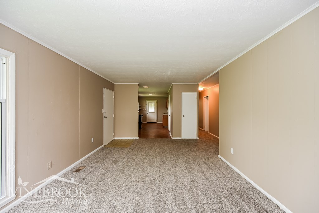 A large, empty room with carpeted flooring and white walls.