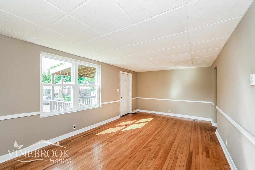 A room with wooden floors and a window showing an outdoor balcony.
