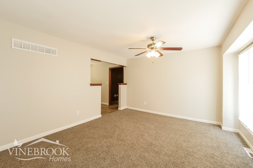 A room with a ceiling fan and a door in the background.