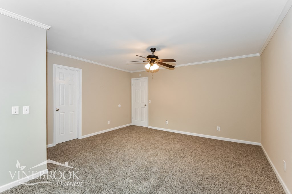a empty living room with a ceiling fan and white doors