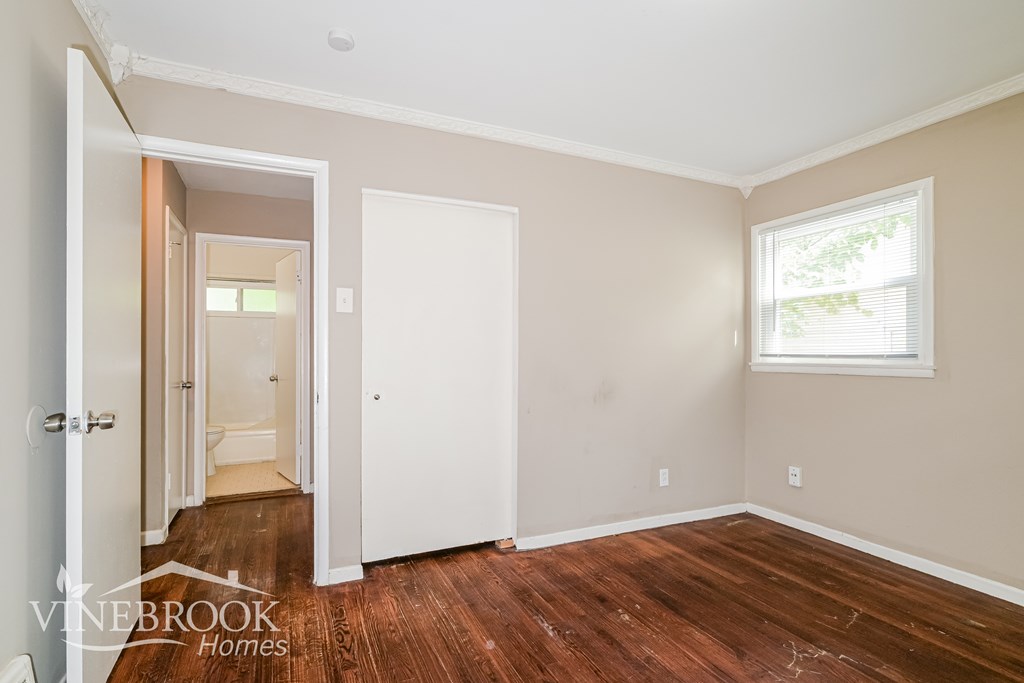A room with a wooden floor and a window with a white frame.