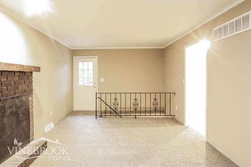 an empty living room with a fireplace and a balcony
