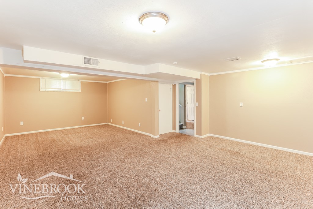 a empty living room with carpet and a door to a bathroom