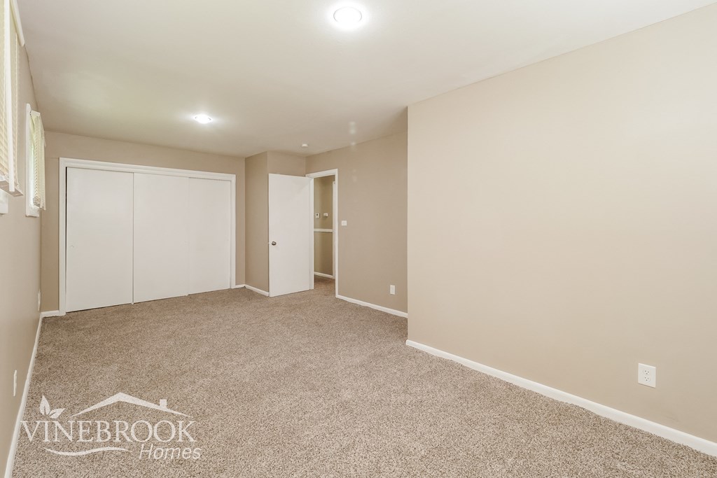 a living room with carpet and a door to a closet