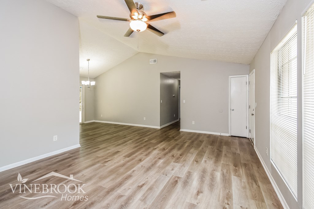 the living room and dining room with wood flooring and a ceiling fan