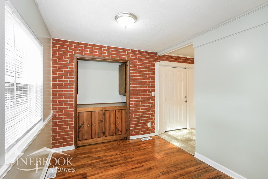 a living room with wood floors and a brick wall and a white door