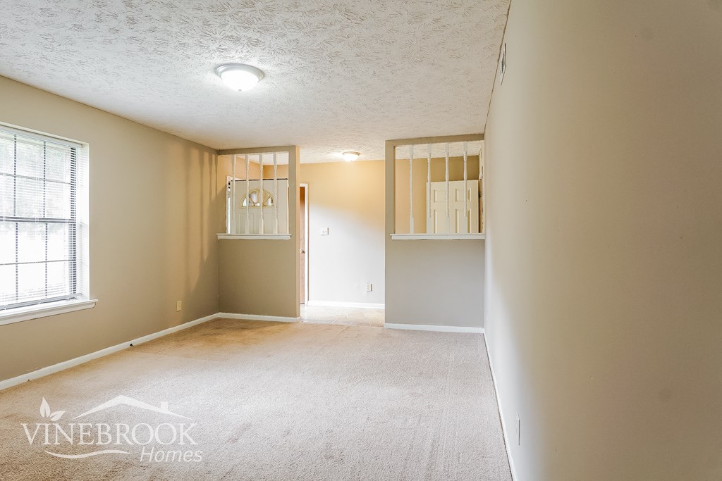 an empty living room with a white carpet and a window