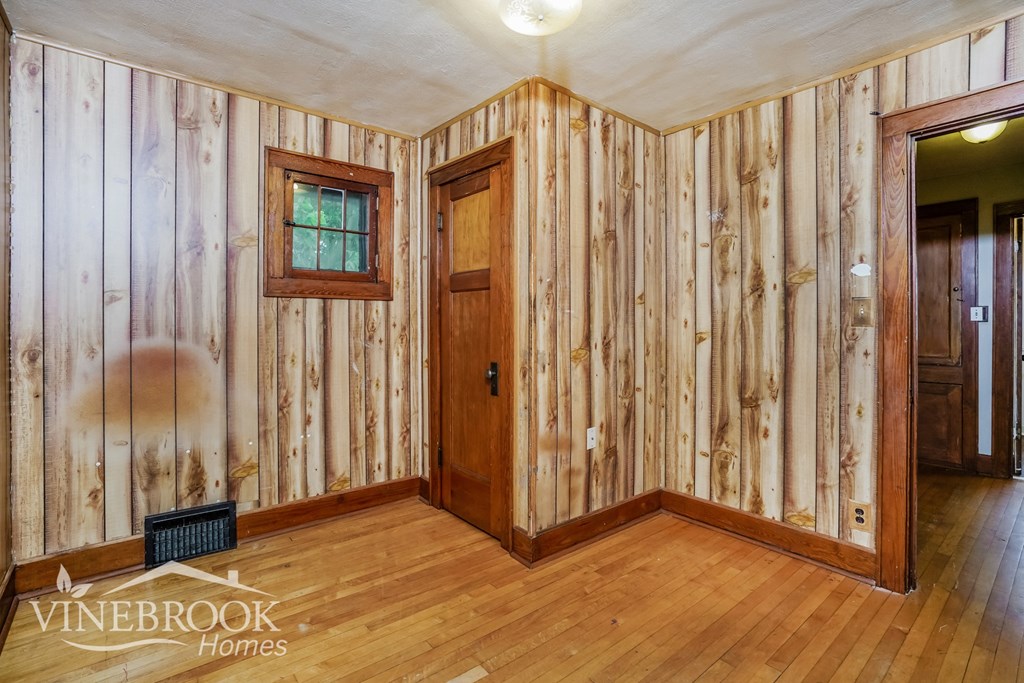 the living room is clad in wood paneling and has a wood floor