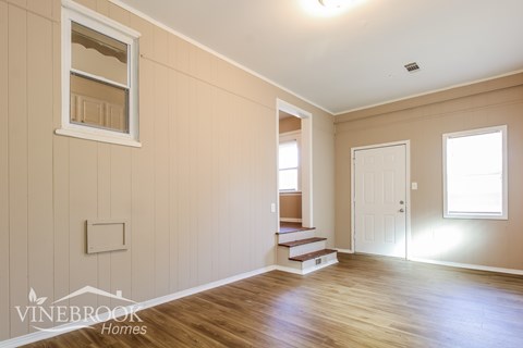 A room with wooden floors and a window with sunlight coming through.