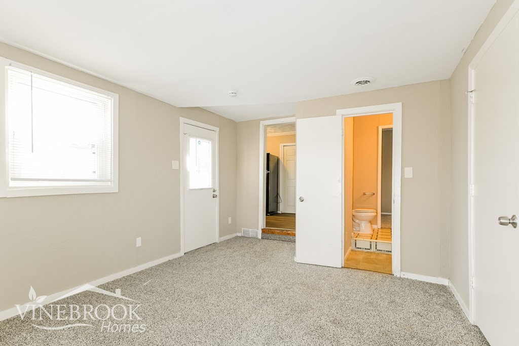 A room with a carpeted floor and a doorway leading to another room.