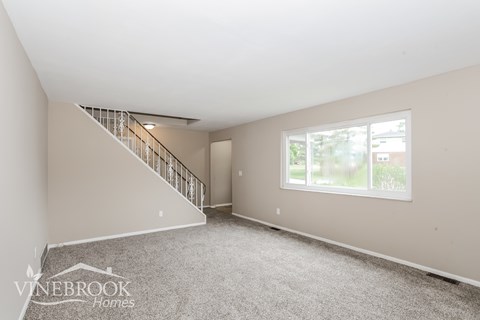 A spacious room with a staircase and a window.