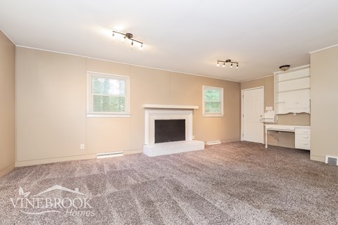 A living room with a fireplace and a carpet on the floor.