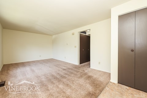 A room with a carpeted floor and a door on the right side.