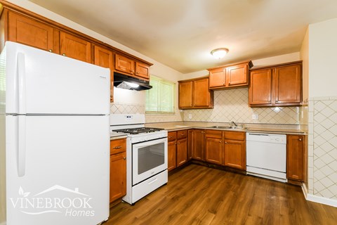 A kitchen with wooden cabinets and a white fridge.