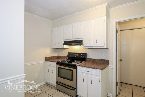 A kitchen with white cabinets and a granite countertop.