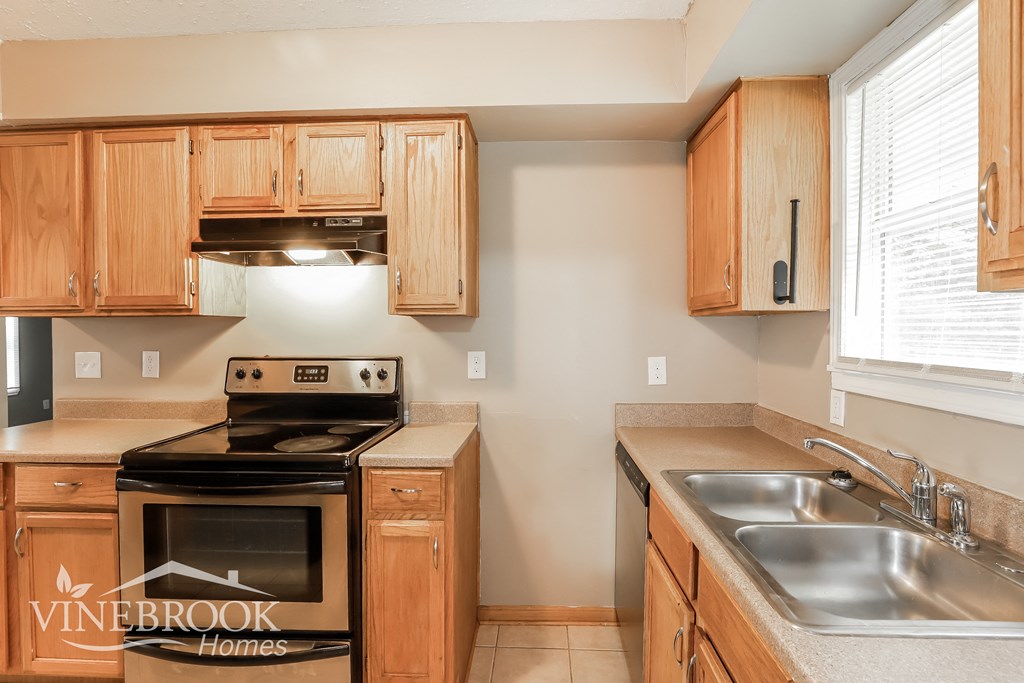 a kitchen with wooden cabinets and a stove and a sink