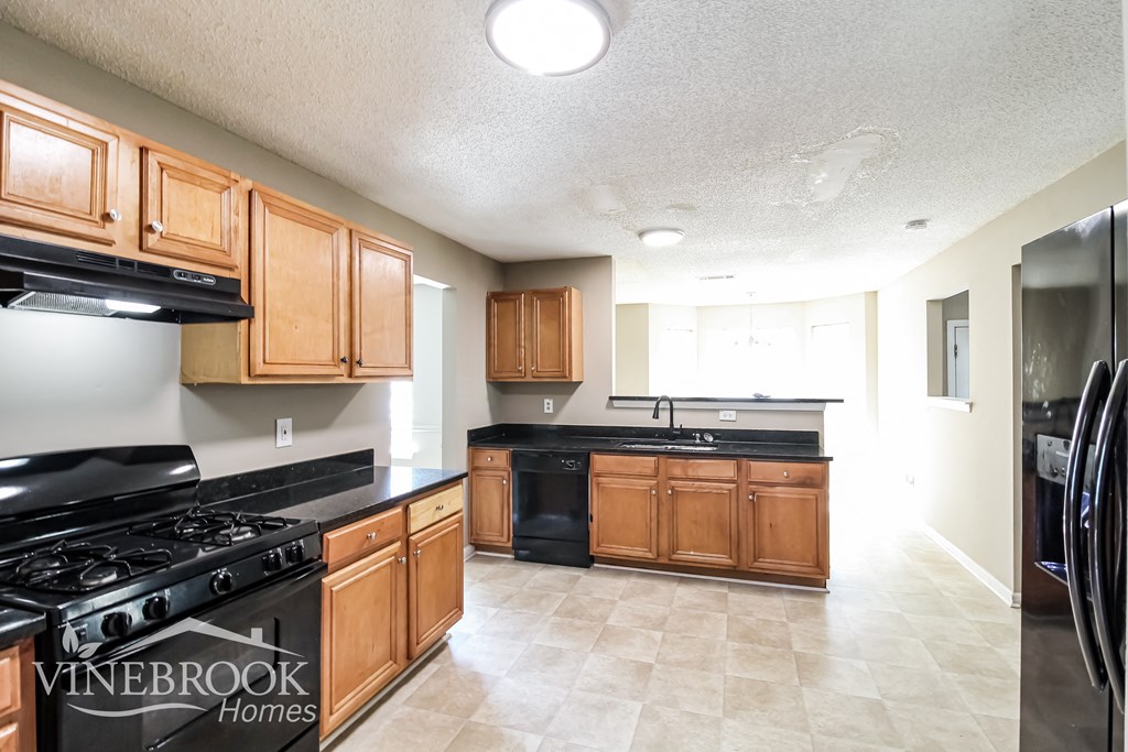a kitchen with wood cabinets and black counter tops and a stove top oven