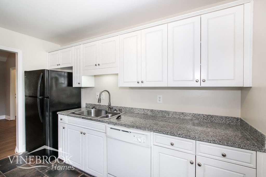 a white kitchen with granite counter tops and white cabinets