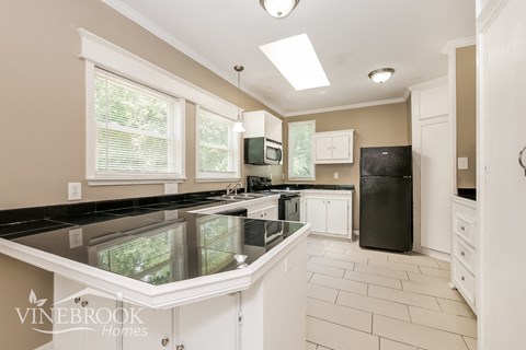 a large kitchen with black counters and white appliances and a glass counter top