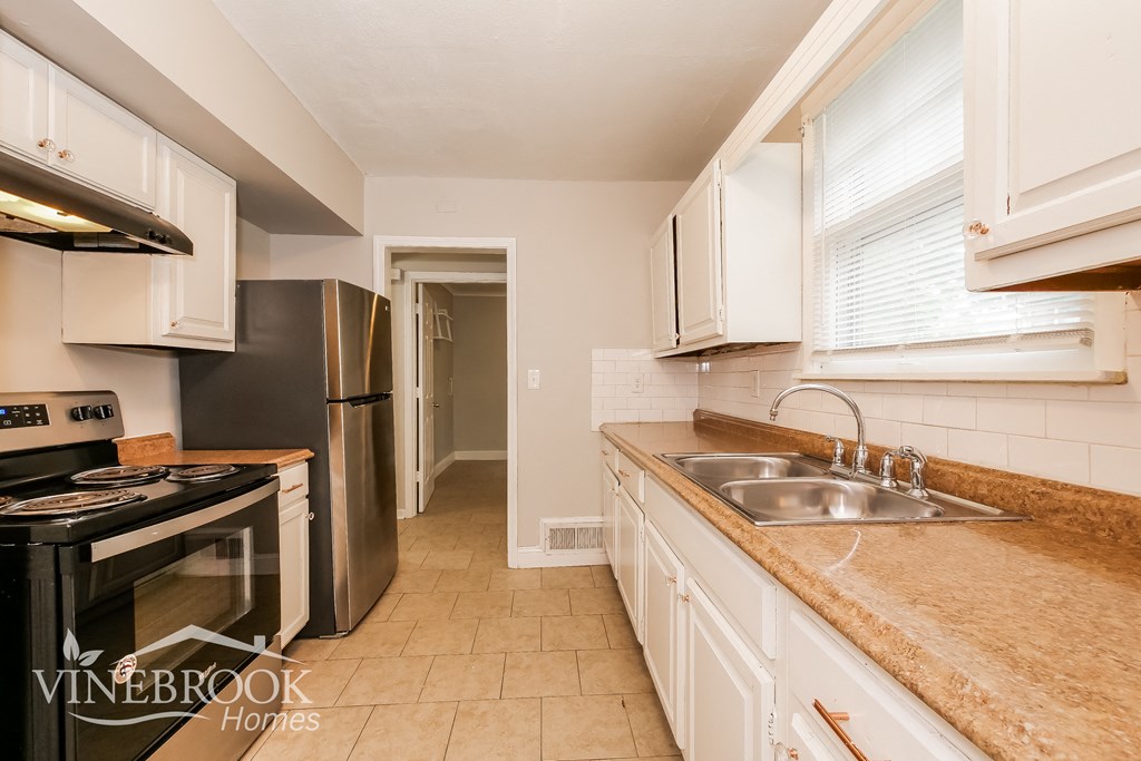 a kitchen with white cabinets and granite counter tops and a black stove and refrigerator