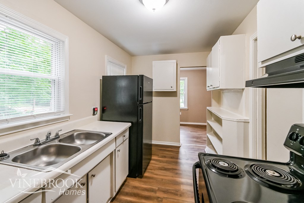 a kitchen with white cabinets and black appliances and a black refrigerator