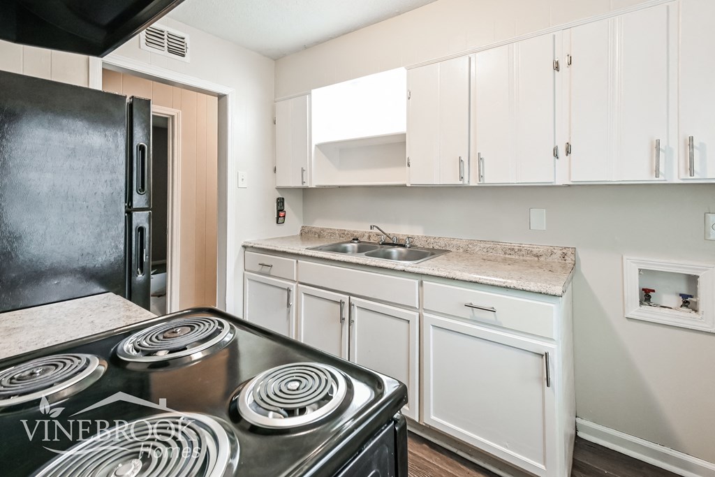 a kitchen with white cabinets and a black stove and refrigerator
