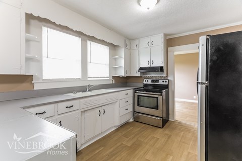 a renovated kitchen with white cabinets and stainless steel appliances