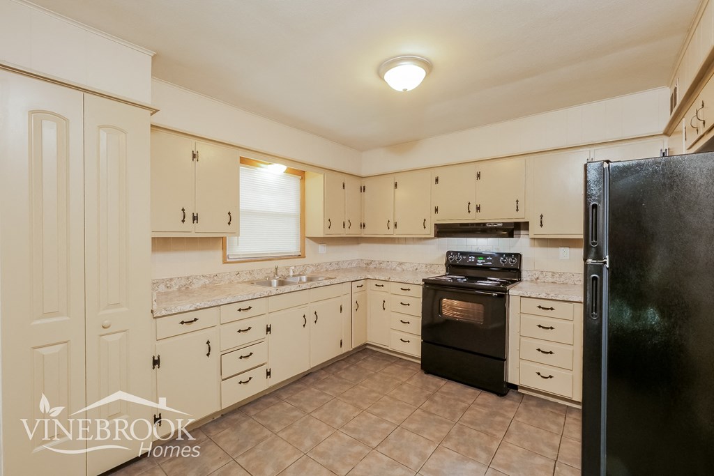 a kitchen with white cabinets and black appliances