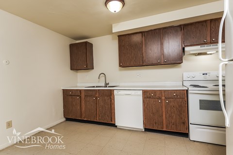 A kitchen with white appliances and brown cabinets.