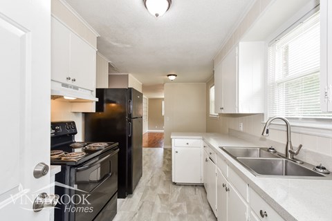 a white kitchen with black appliances and white cabinets