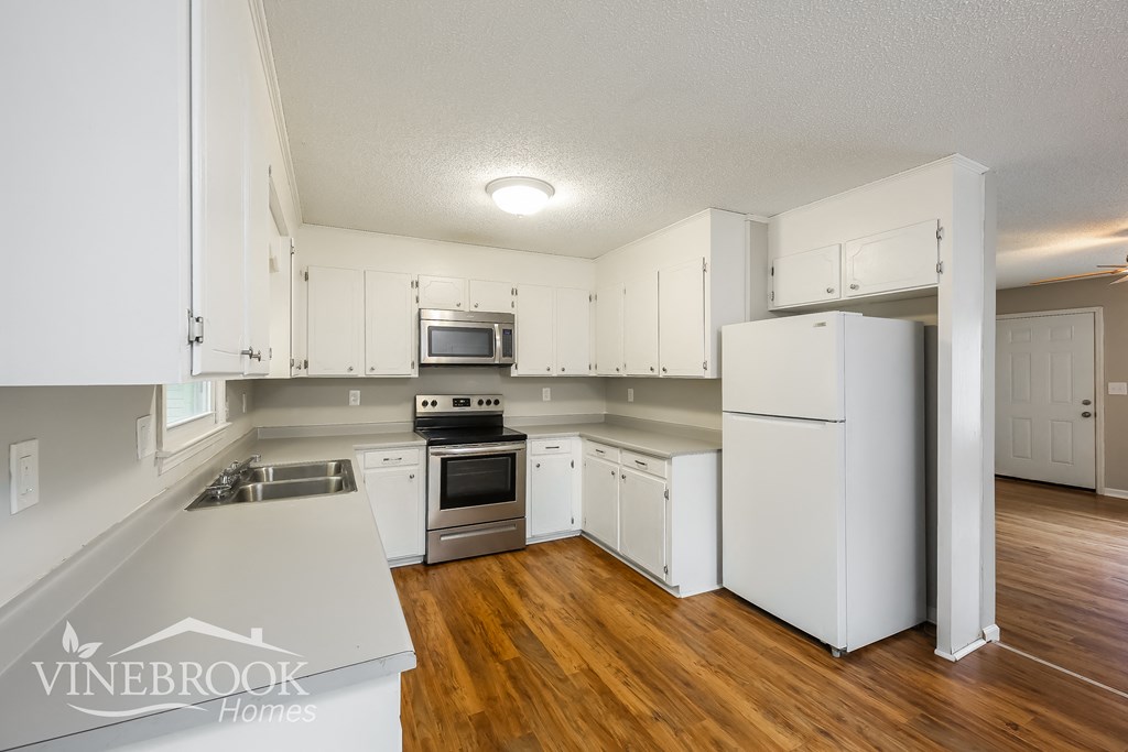 a kitchen with white cabinets and white appliances and a wood floor