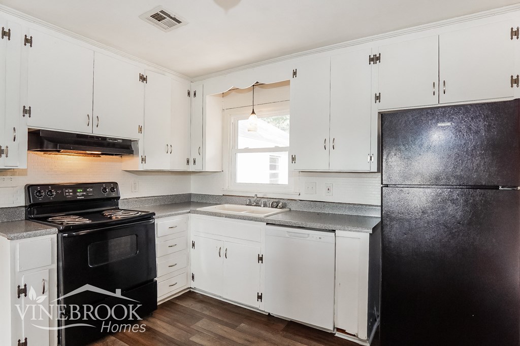 a white kitchen with black appliances and white cabinets