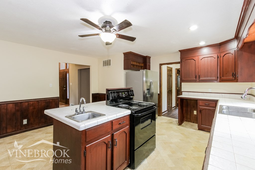 a kitchen with a sink and a stove and a ceiling fan