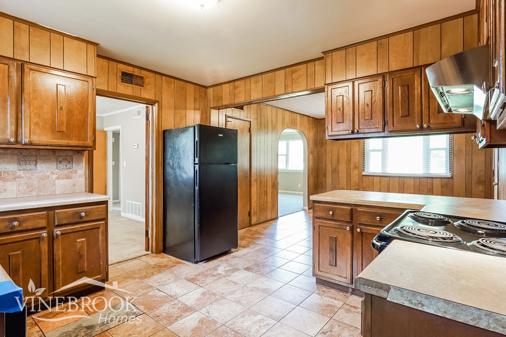 a kitchen with wooden cabinets and a black refrigerator
