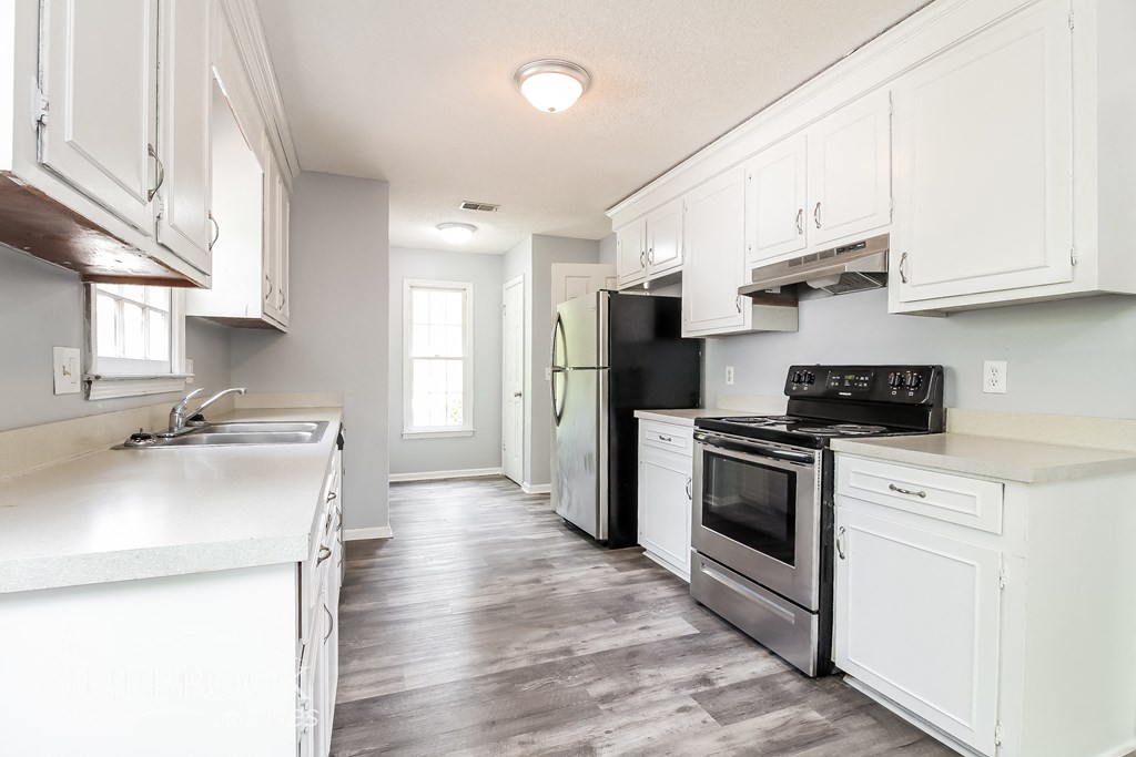 an empty kitchen with white cabinets and stainless steel appliances