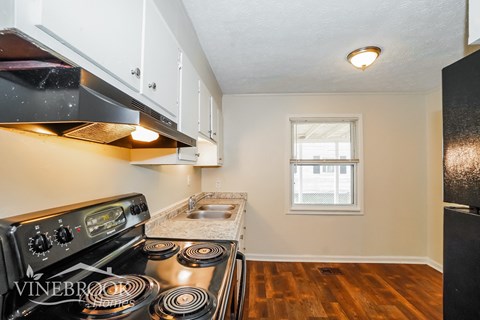 a kitchen with a stove and a sink and a window