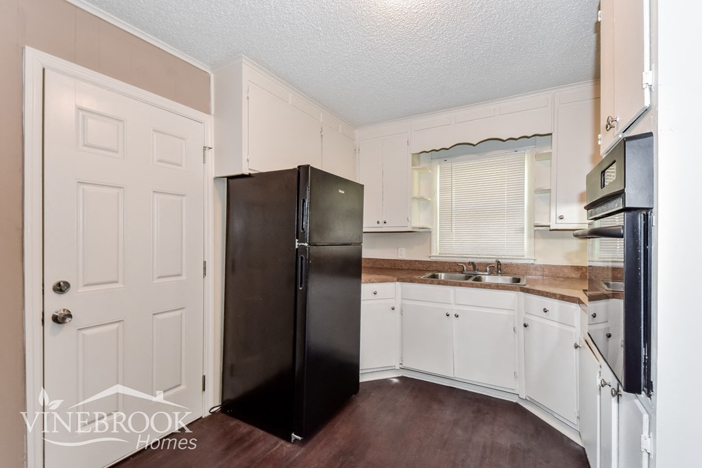 a kitchen with white cabinets and a black refrigerator