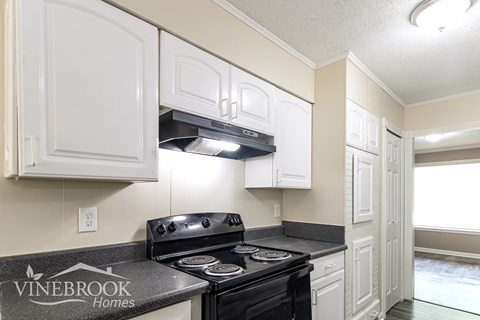 A kitchen with a black stove top oven and white cabinets.