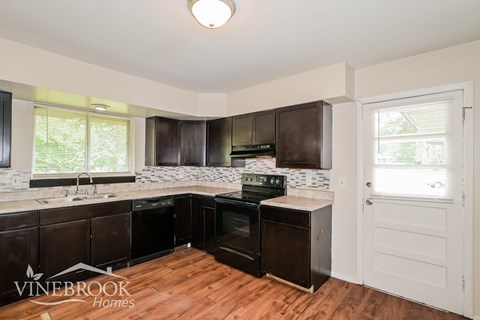 A kitchen with dark wood cabinets and a white door.