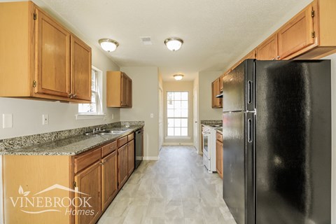 a kitchen with wooden cabinets and a black refrigerator