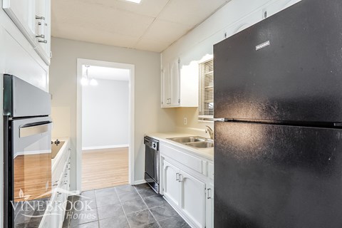 a kitchen with white cabinets and a black refrigerator