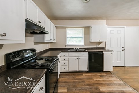 a kitchen with white cabinets and a stove and a sink