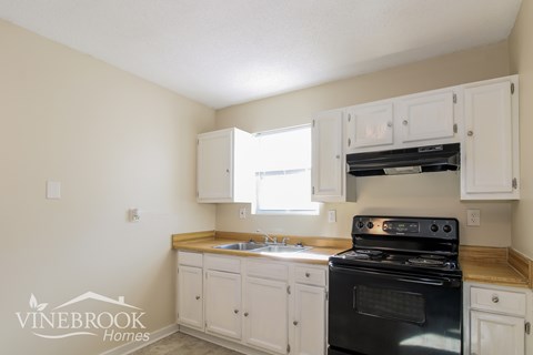 A kitchen with white cabinets and a black stove top oven.