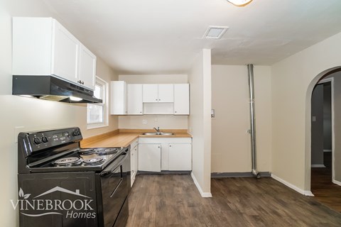 A kitchen with a black stove top oven and white cabinets.