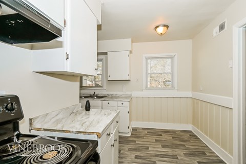 A kitchen with a black stove top oven and white cabinets.