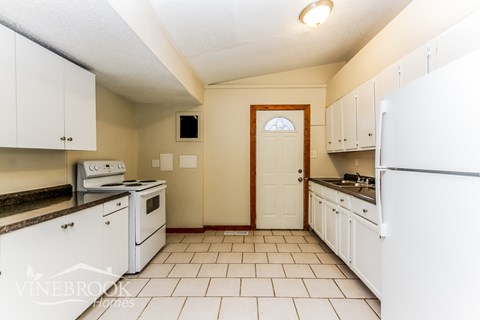 A kitchen with white appliances and cabinets.